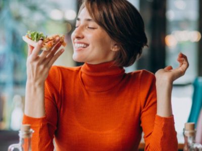 Mujer comiendo un trozo de pizza