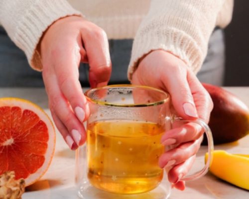 Mujer sosteniendo un vaso con un líquido amarillo